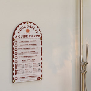 Pool safety guide to CPR on a white wall next to a shower.