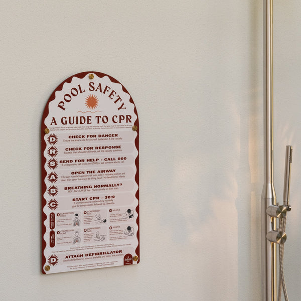 Pool safety guide to CPR on a white wall next to a shower.