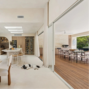 Modern kitchen and dining area with white walls and wooden flooring, looking to outdoor area with sage green pool sign.
