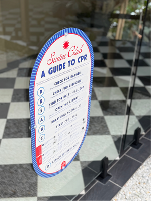 CPR pool safety sign on a glass pool fence with a checkered floor background